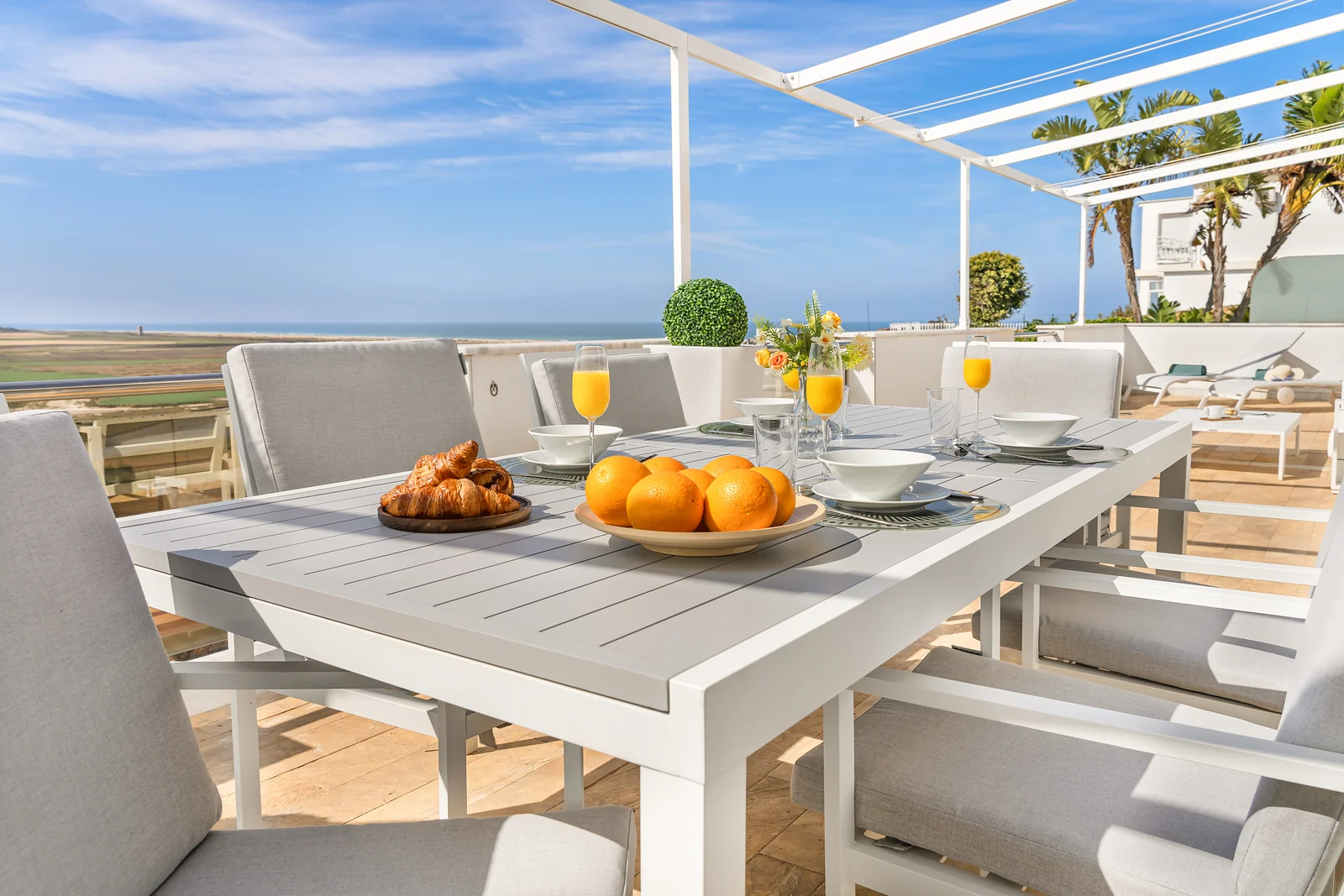 Gedeckter Frühstückstisch mit Orangen und Croissants auf der Dachterrasse von La Terraza Río y Mar in Conil